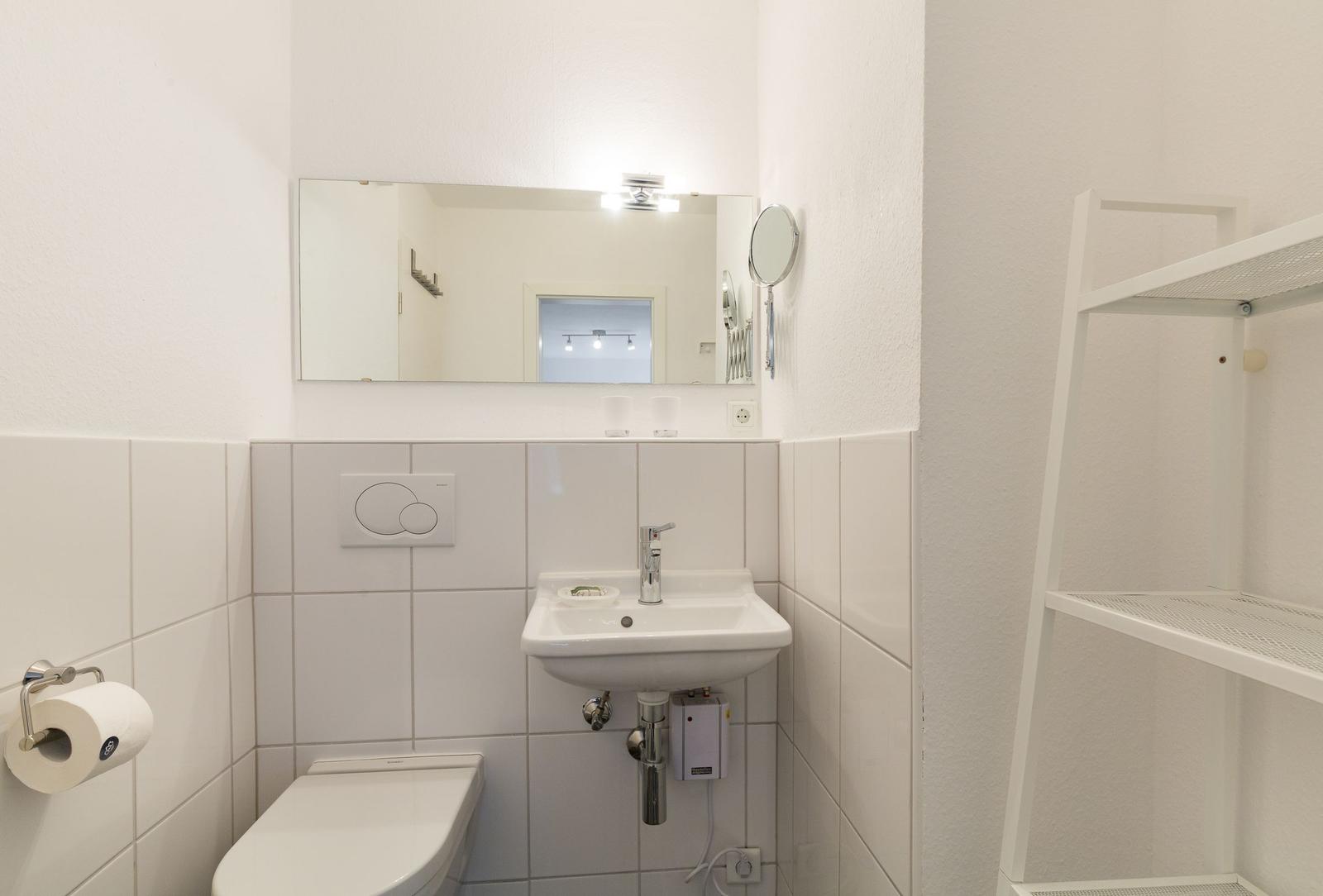 Bathroom with toilet, sink, and mirror on the wall.