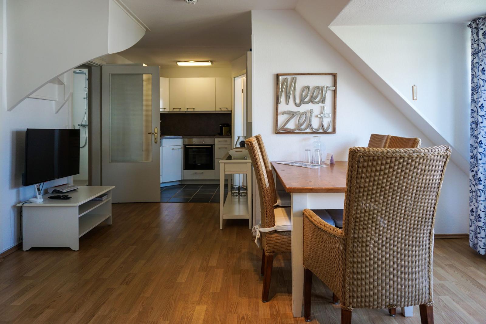 Dining area with table and chairs, kitchen and living area with TV