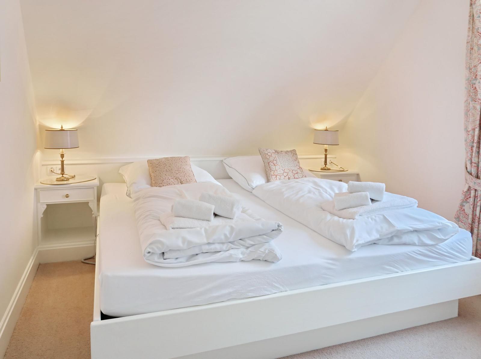 Schlafzimmer mit Doppelbett, zwei Nachttischen und Lampen.