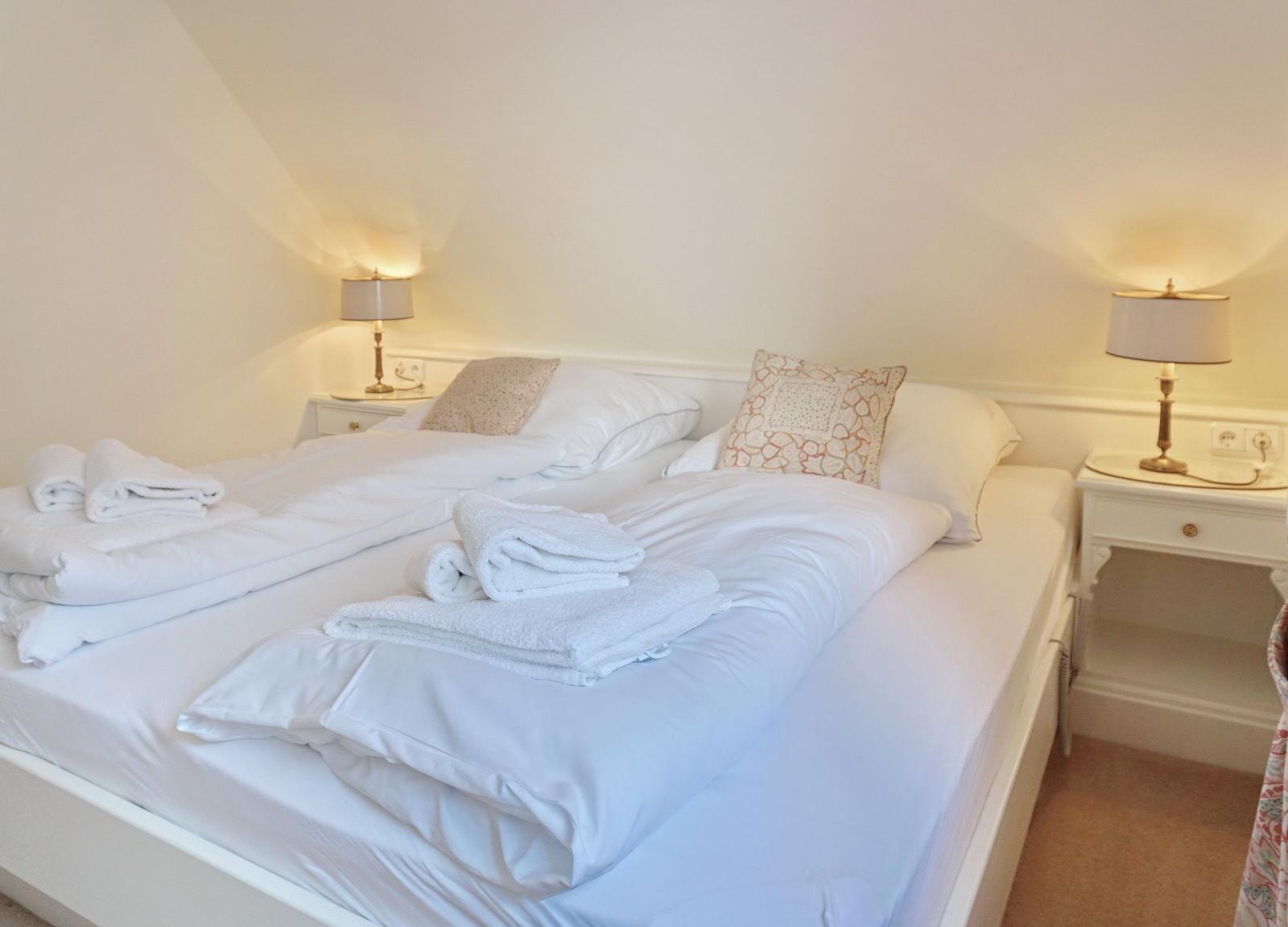 Schlafzimmer mit Doppelbett, zwei Nachttischen und Lampen.