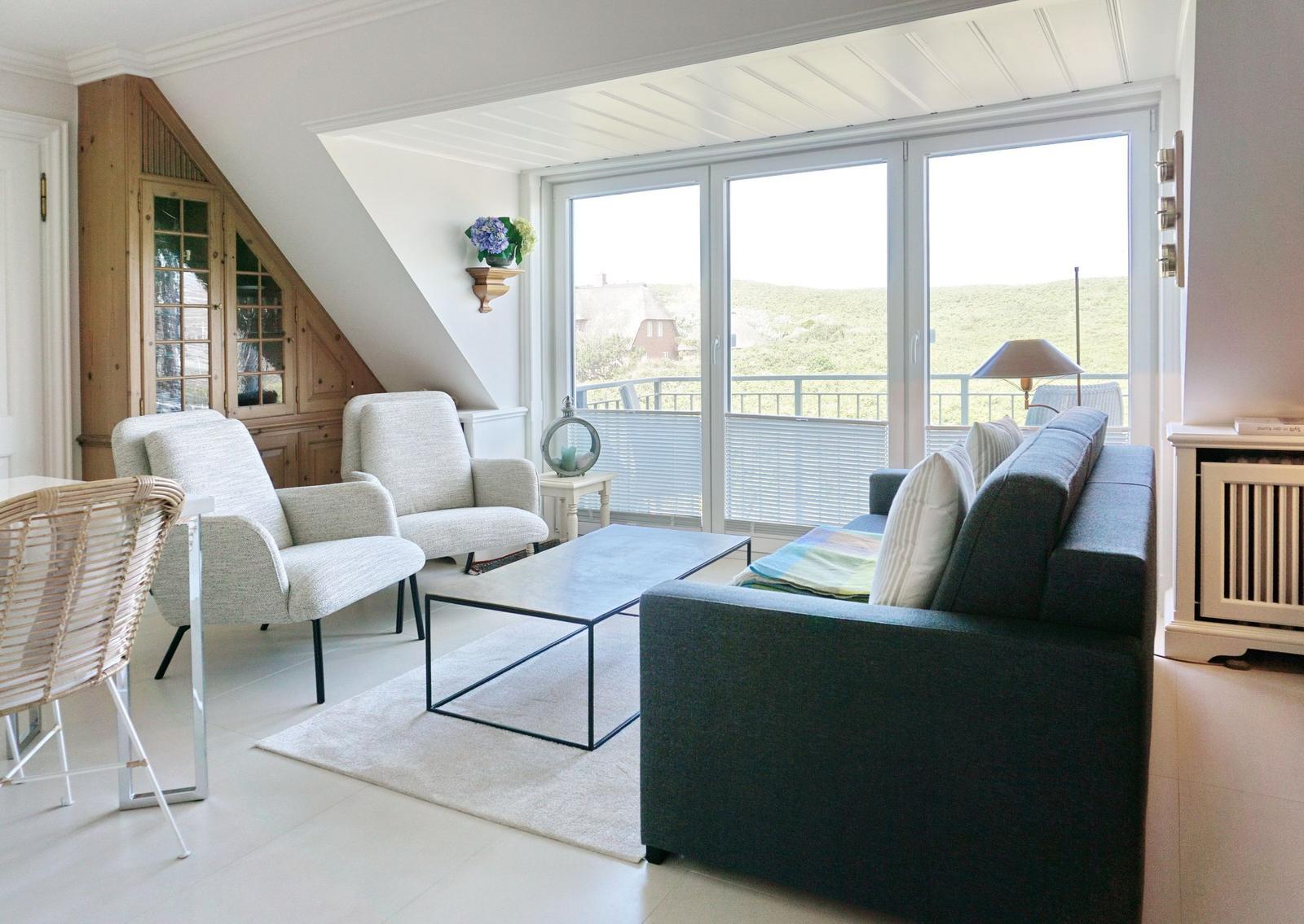 Wohnzimmer mit Sofa, Sesseln und Balkonansicht