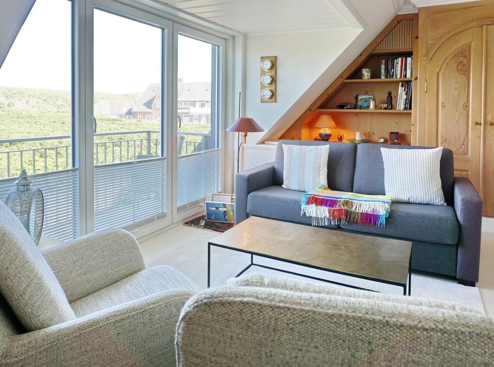 Wohnzimmer mit Sofa, Sitzgelegenheiten und Balkonblick.