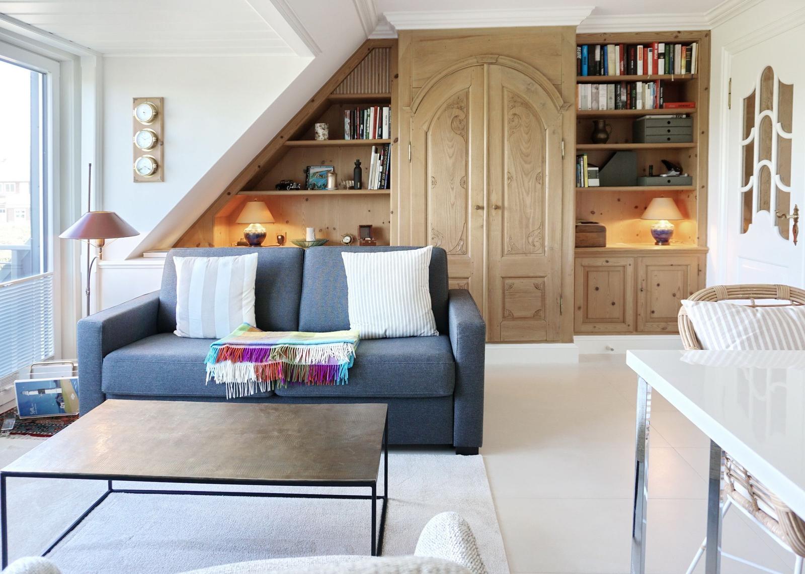 Ein Wohnzimmer mit Sofa, Couchtisch und Holzregalen. 
