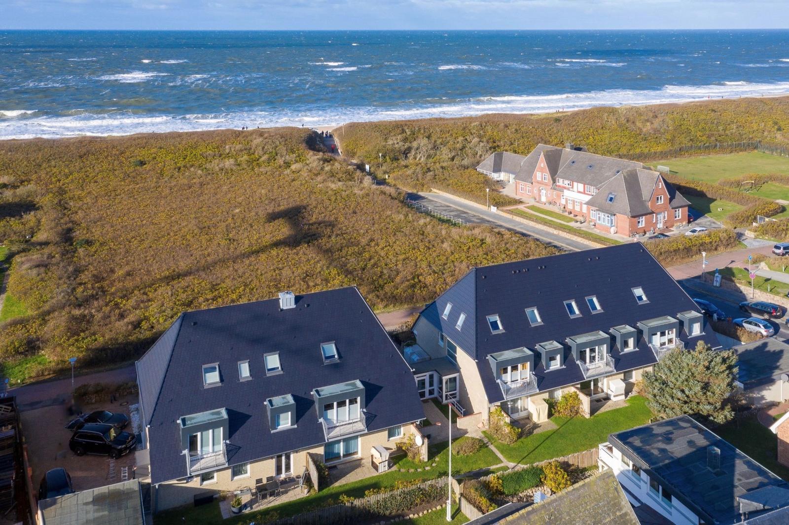 Modernes Ferienhaus mit Blick auf das Meer und grünen Hügeln.