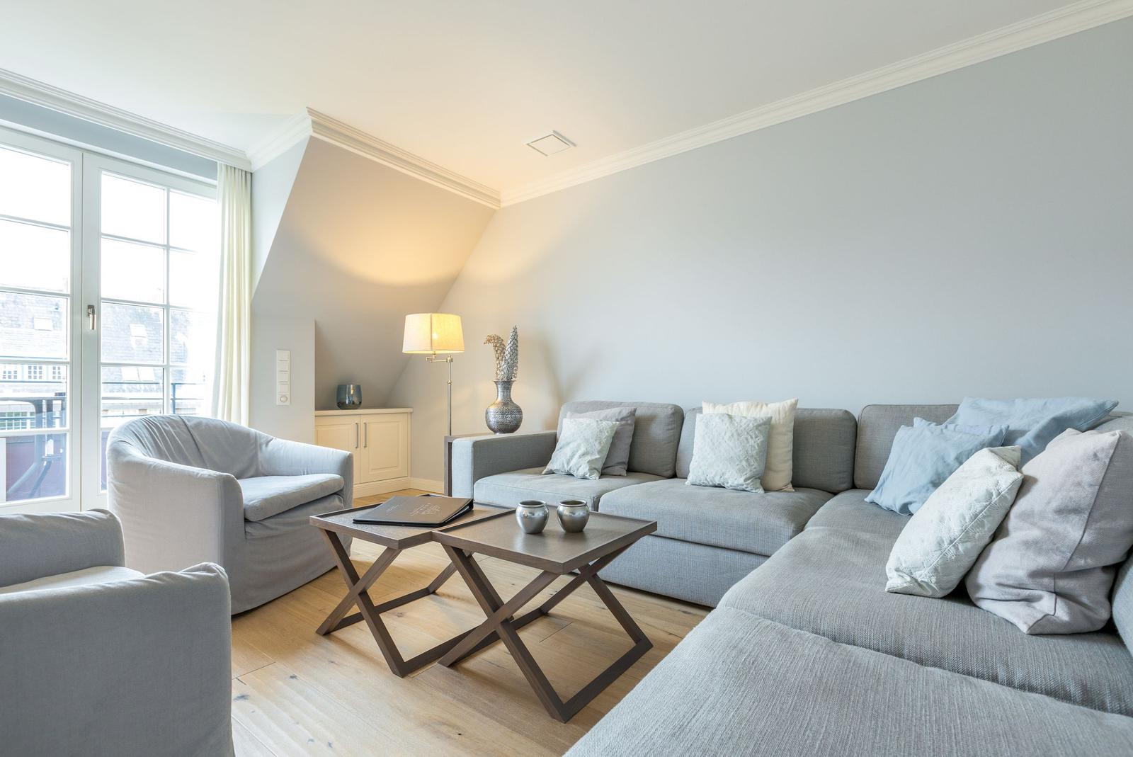 Wohnzimmer mit grauem Sofa, Couchtisch und Fenster.