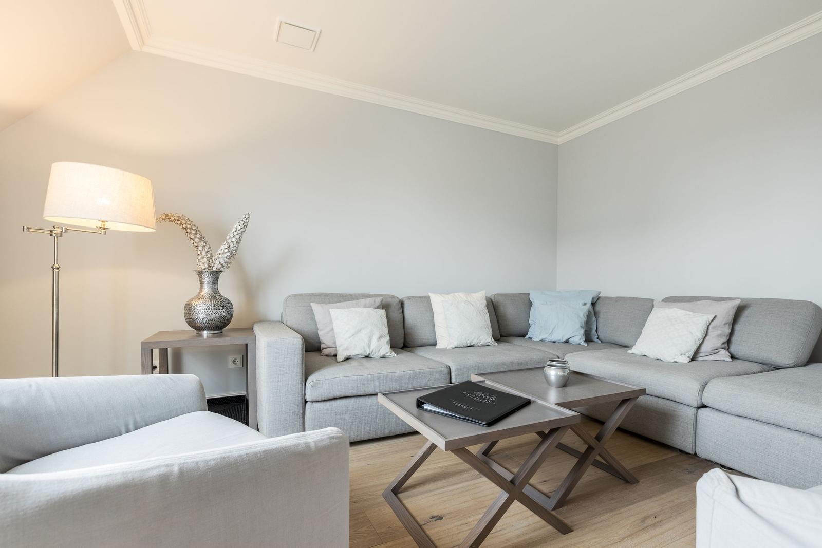 Wohnzimmer mit grauem Sofa, Couchtisch und Stehlampe.