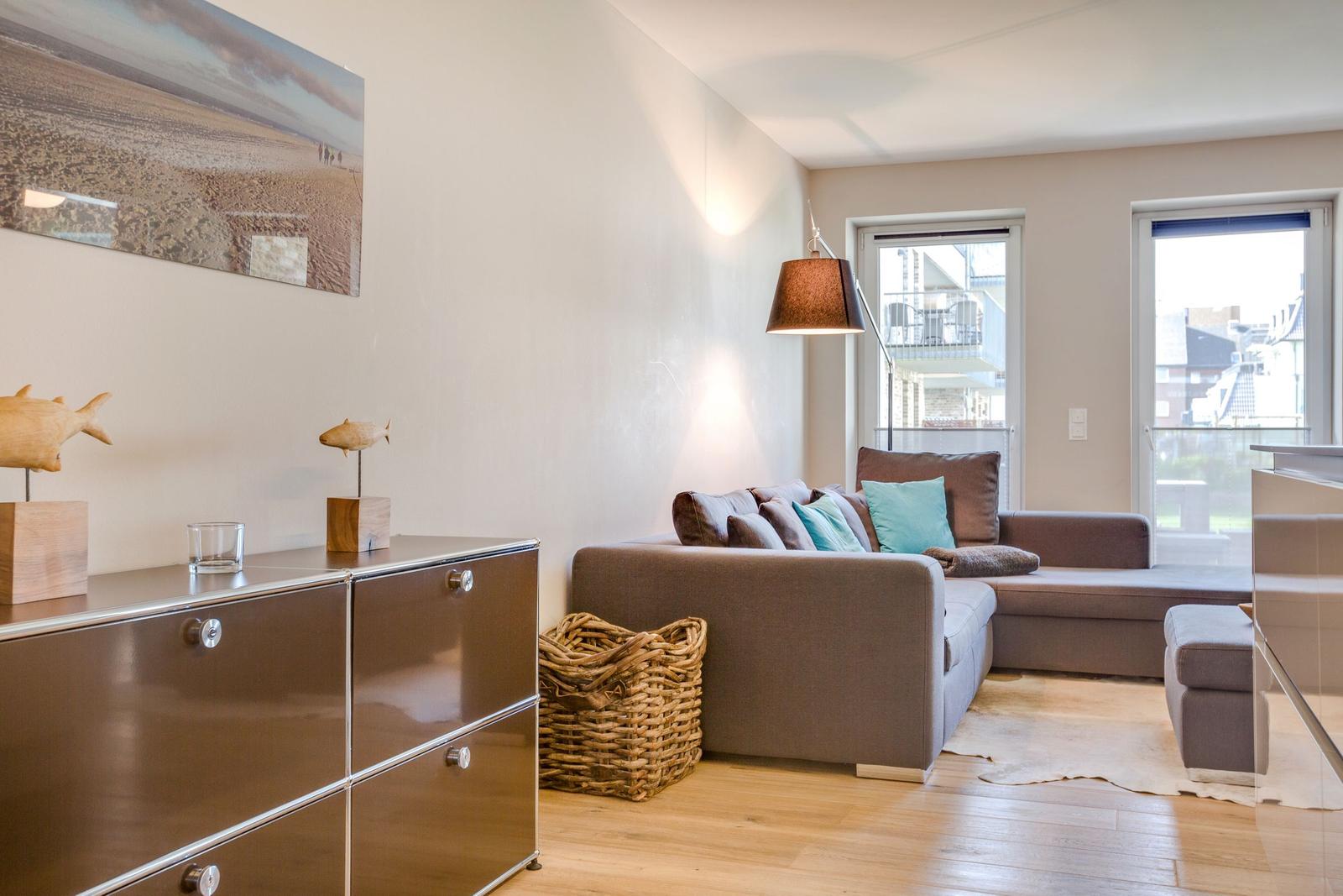 Wohnzimmer mit Sofa, Kissen, Schrank und Wandbild.