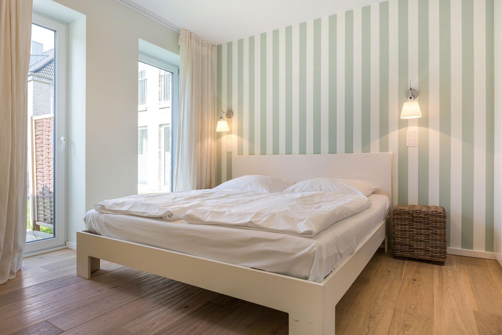 Schlafzimmer mit Bett, Streifenwand und Fenster.