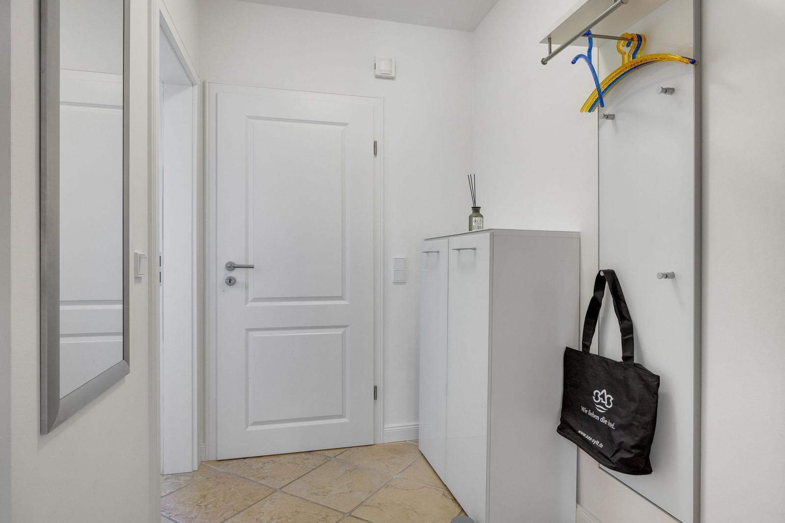 Eingangsbereich mit Schrank, Spiegel und Kleiderhaken.