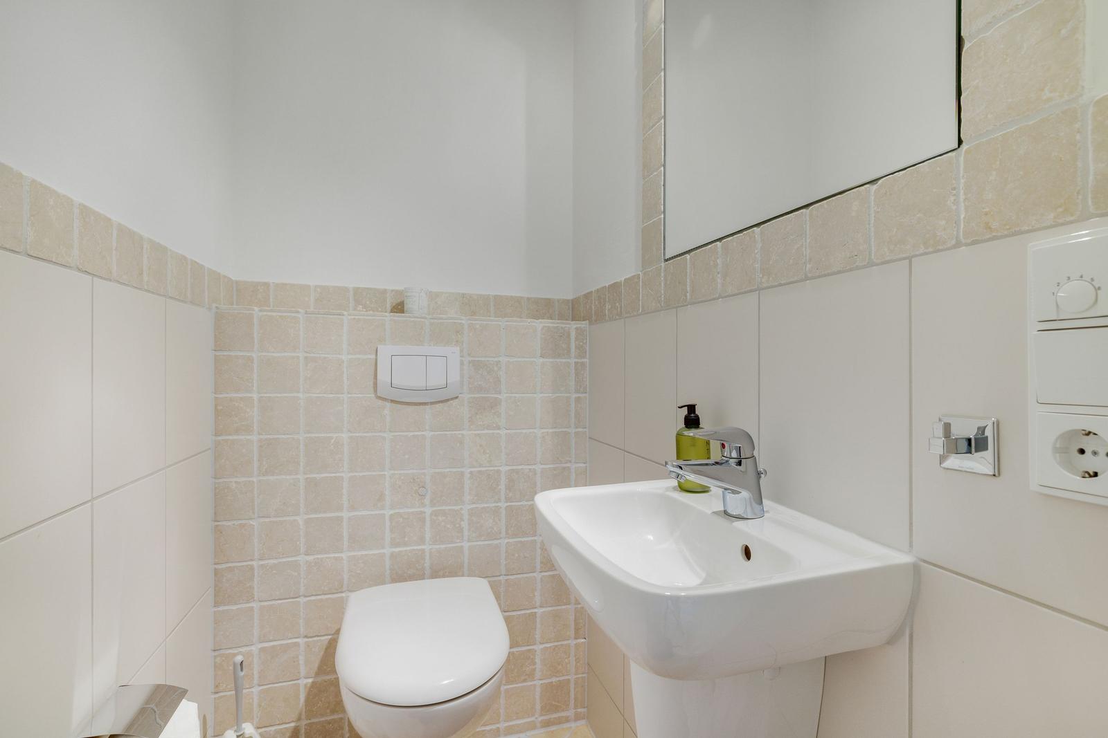 Badezimmer mit Toilette, Waschbecken und Spiegel.