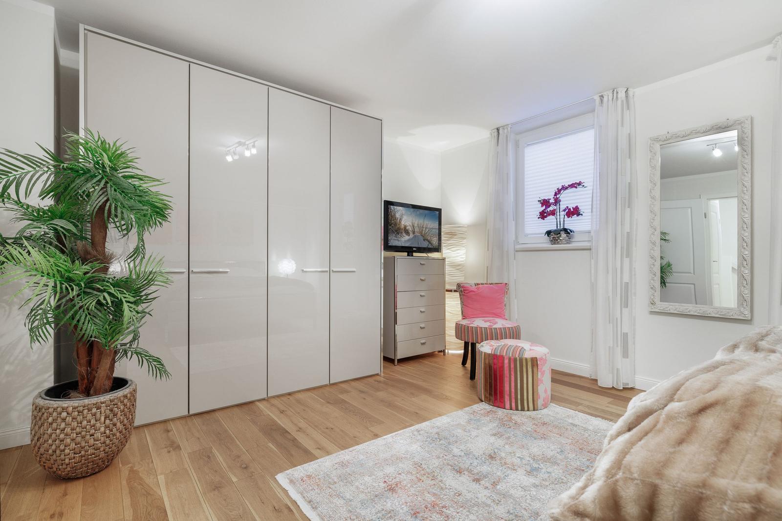 Schlafzimmer mit Kleiderschrank, Fernseher und Sitzgelegenheit