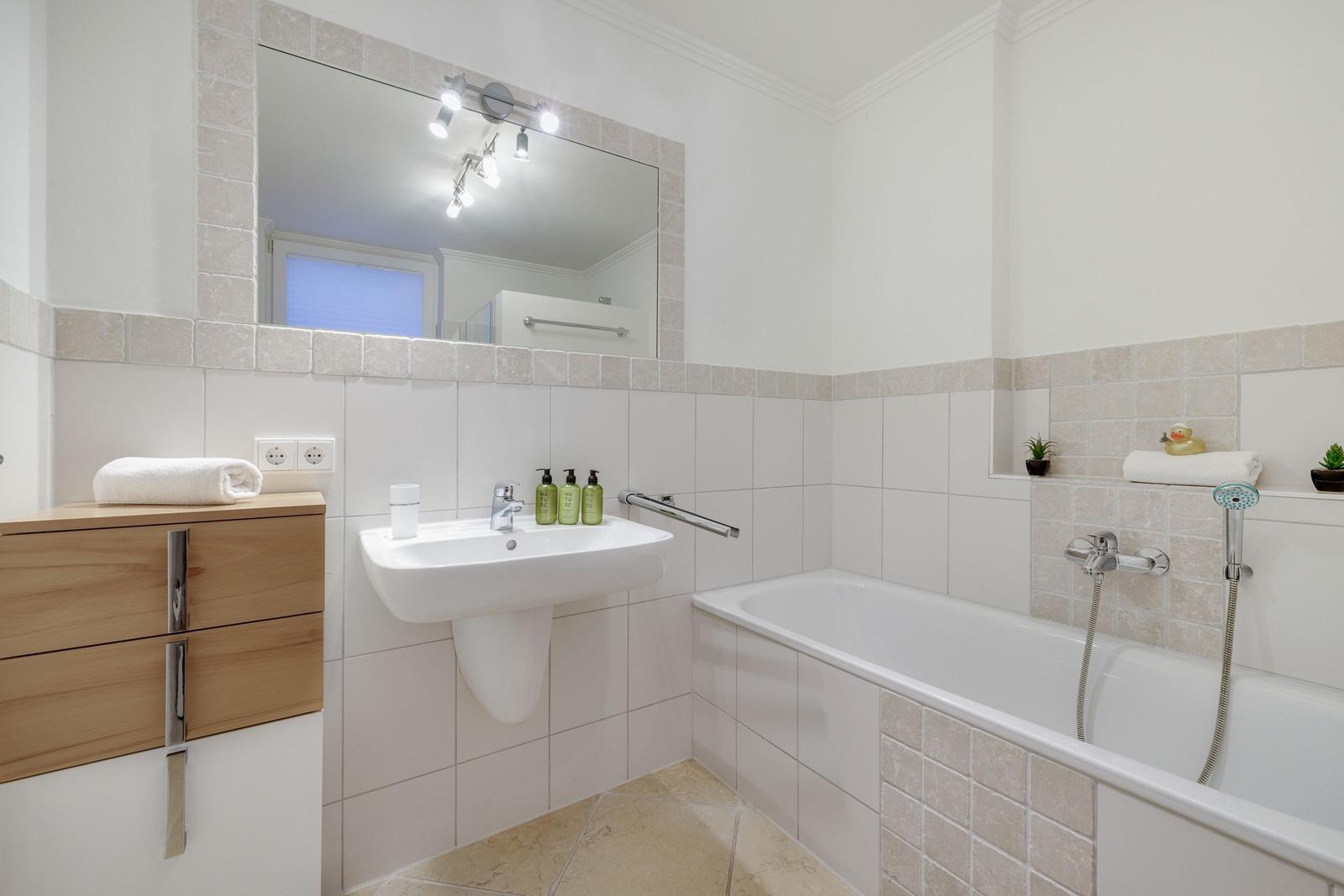 Badezimmer mit Badewanne, Waschbecken und Spiegel
