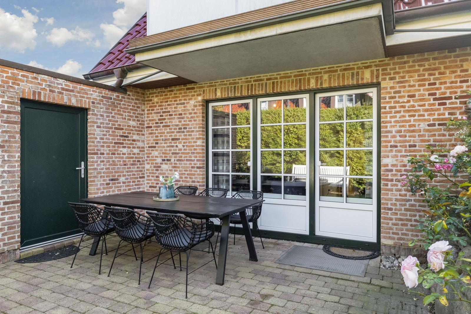 Terrace with table and chairs, glass doors and red roof
