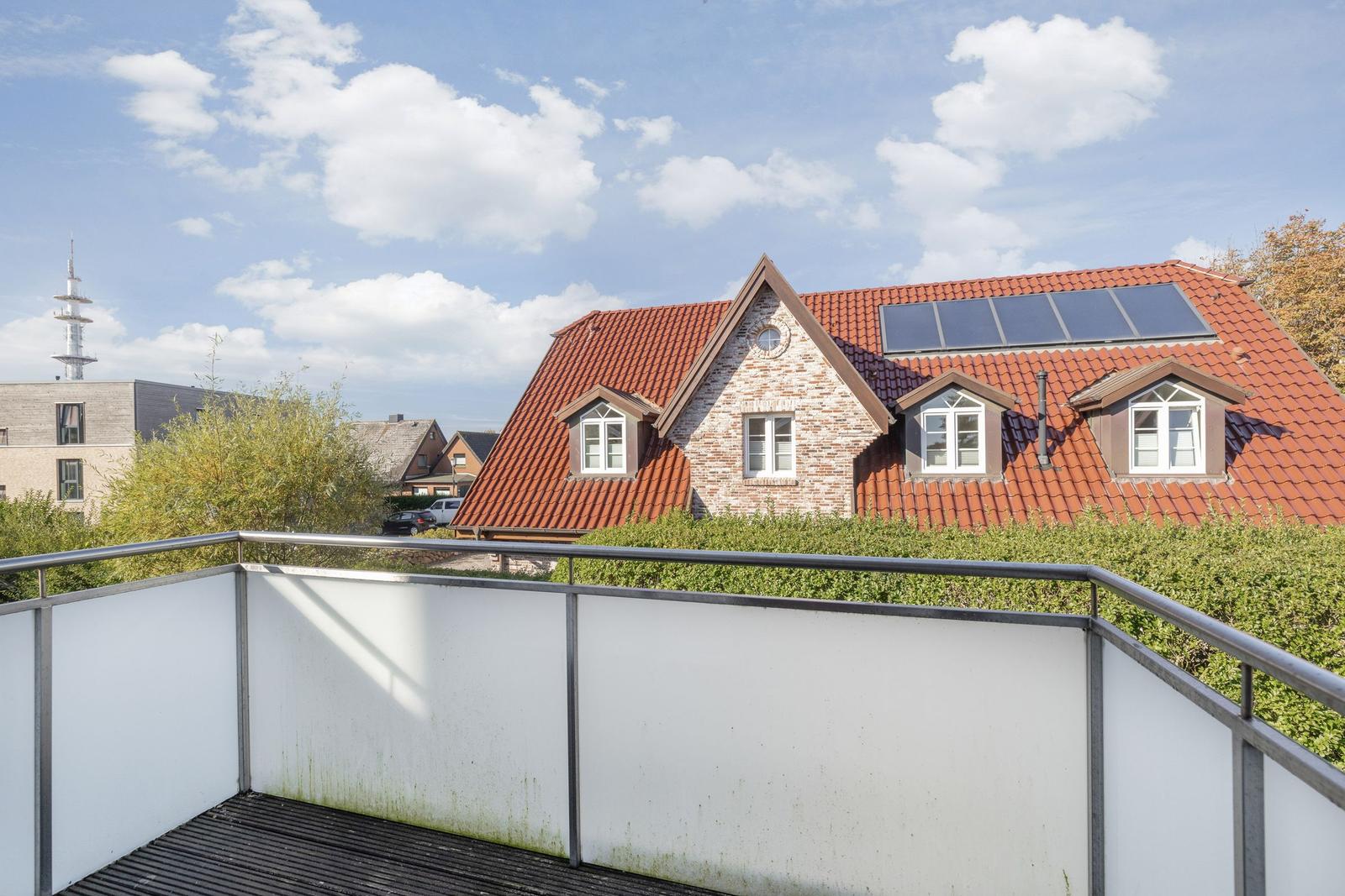 Terrace with view of a house with red roof and solar panels.