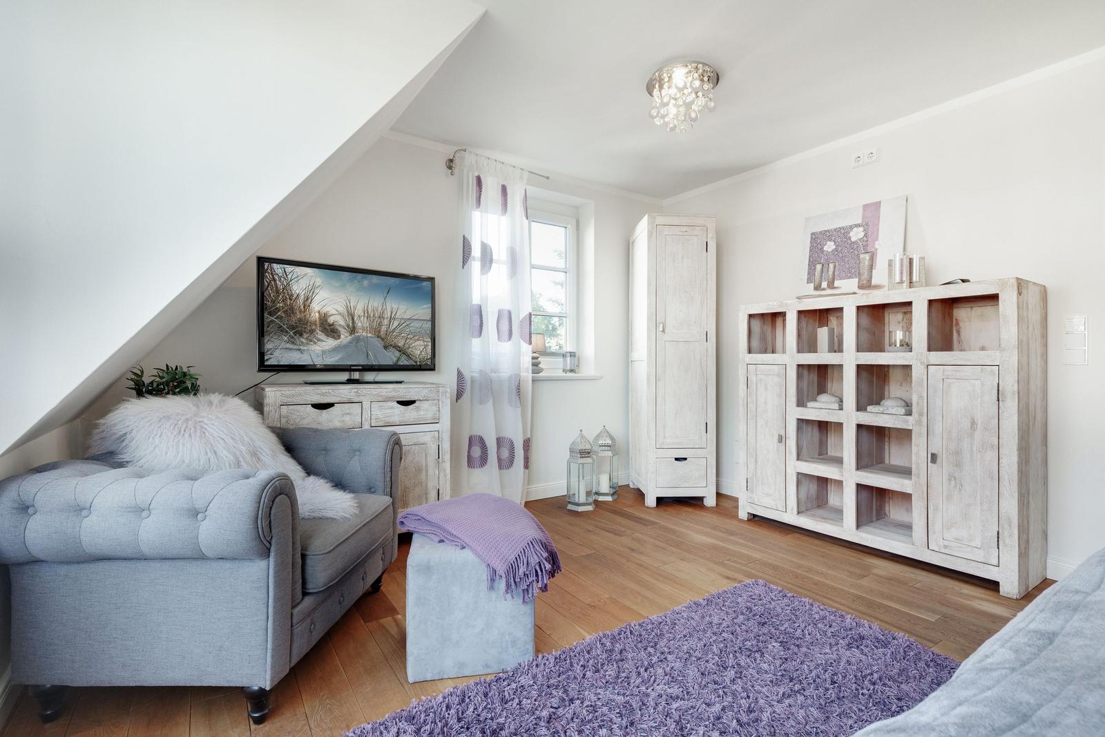 Living room with sofa, TV, and wooden furniture.