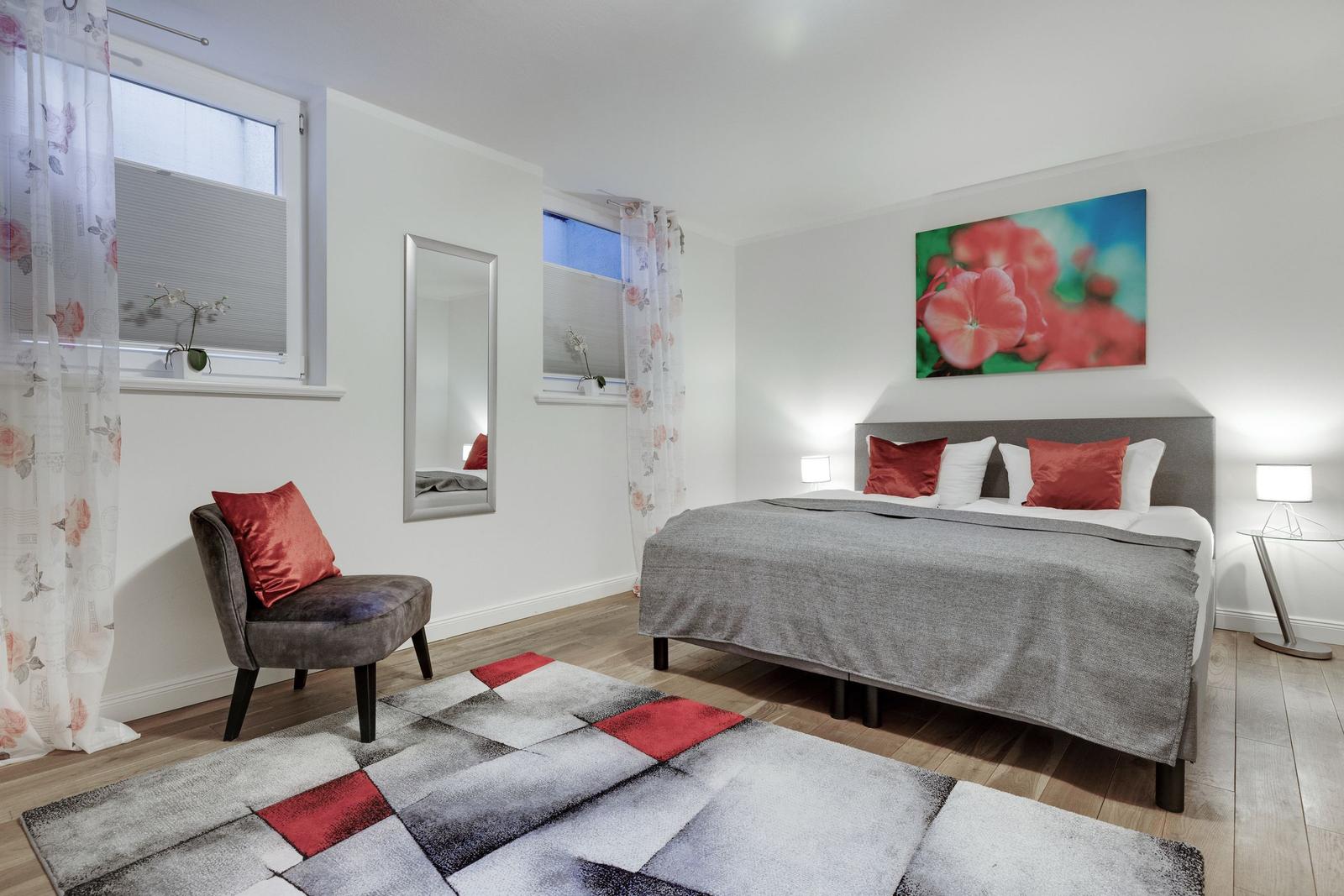 Bedroom with bed, chair, mirror, and wall art.