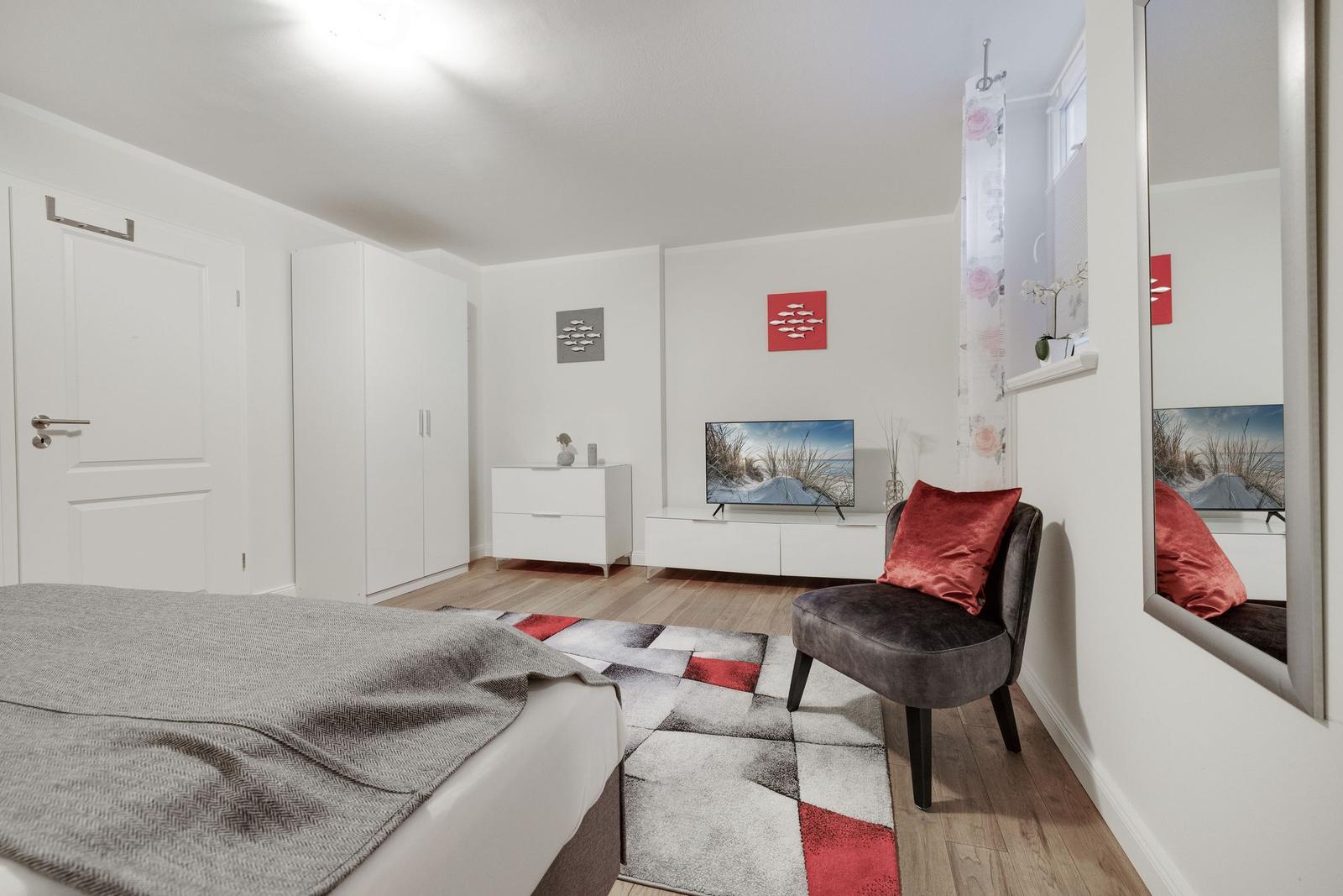 Bedroom with bed, wardrobe, TV, and armchair.