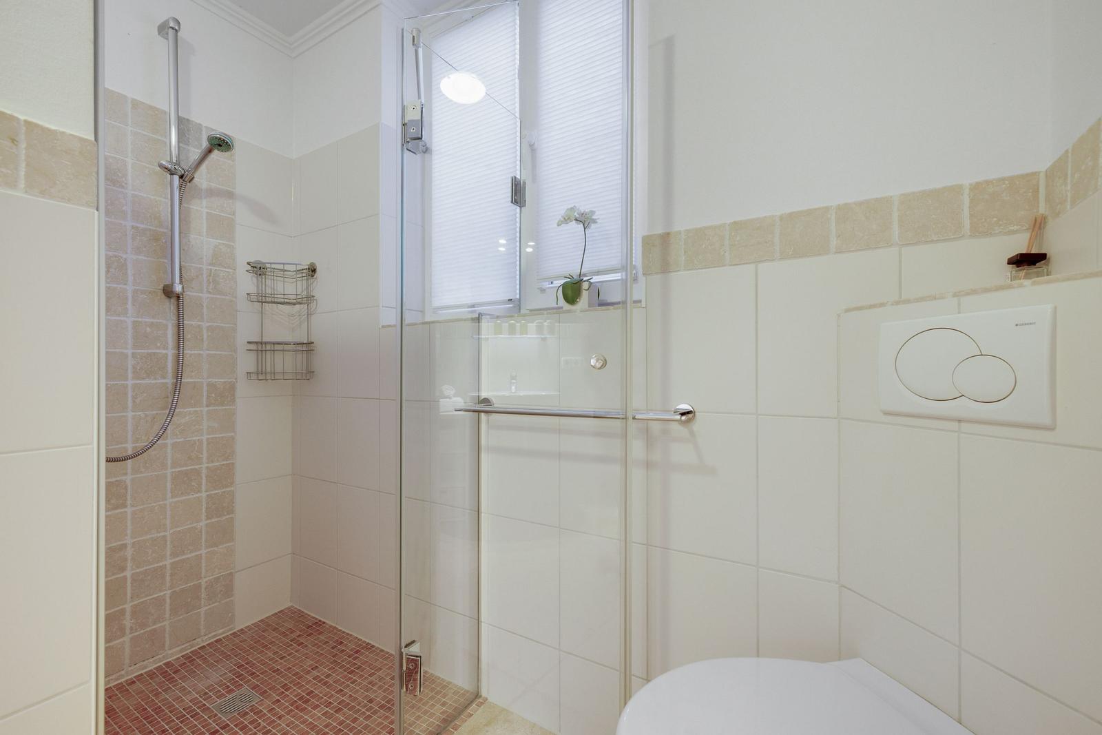 Shower cabin with glass door, window, and toilet