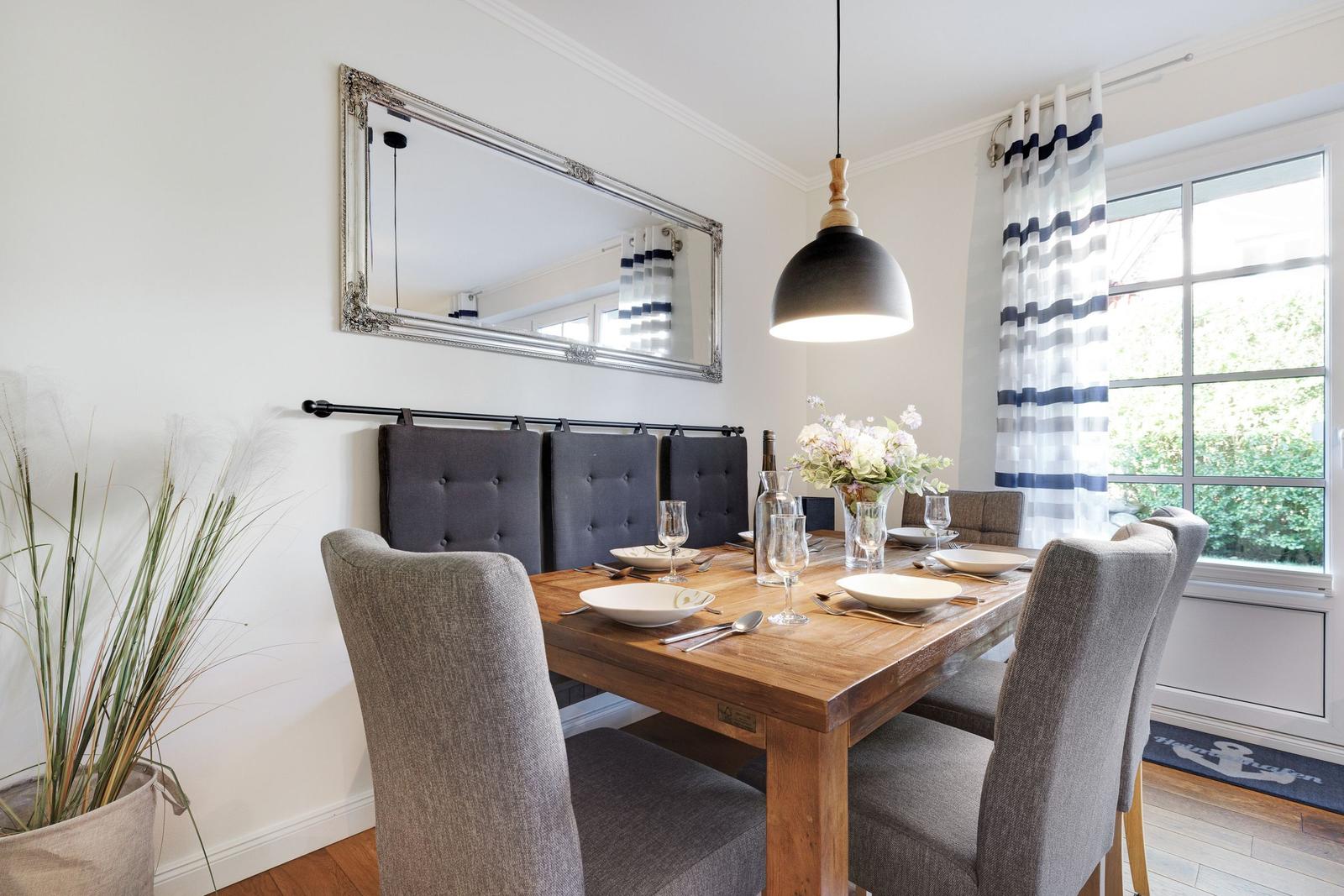 Dining room with wooden table, gray chairs, and mirror frame