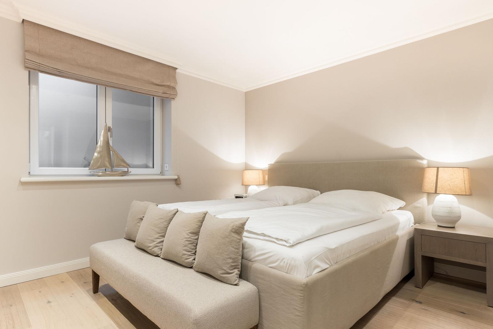 Bedroom with double bed, nightstand, and window with sailboat.