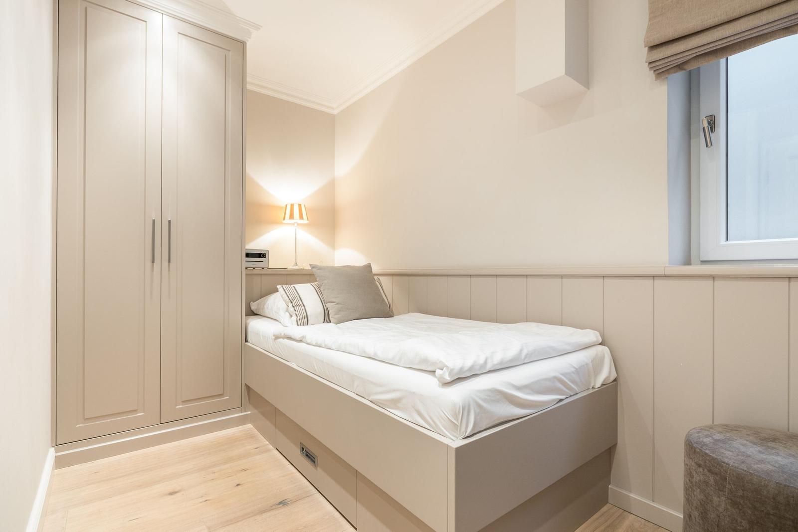 Bedroom with bed, wardrobe, and window.