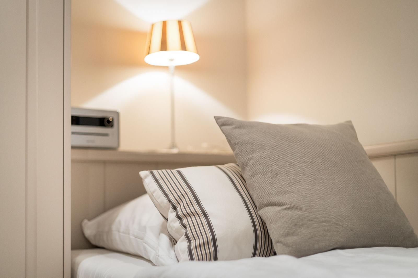 Bed headboard with pillows and bedside lamp.