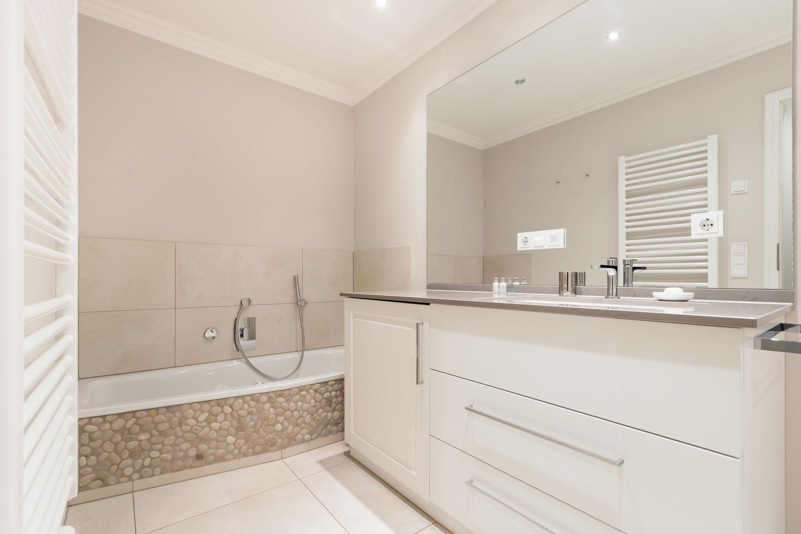 Bathroom with bathtub, mirror cabinet, and heater