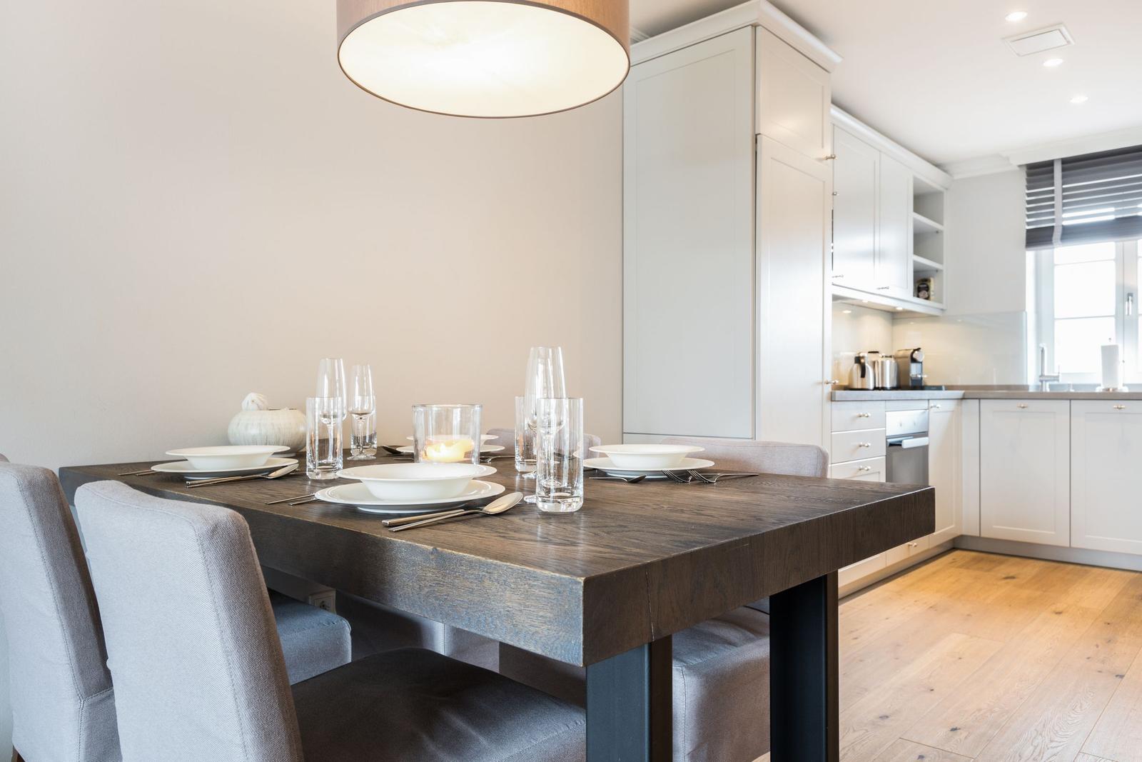 Dining table with chairs and dishes in kitchen with white cabinets
