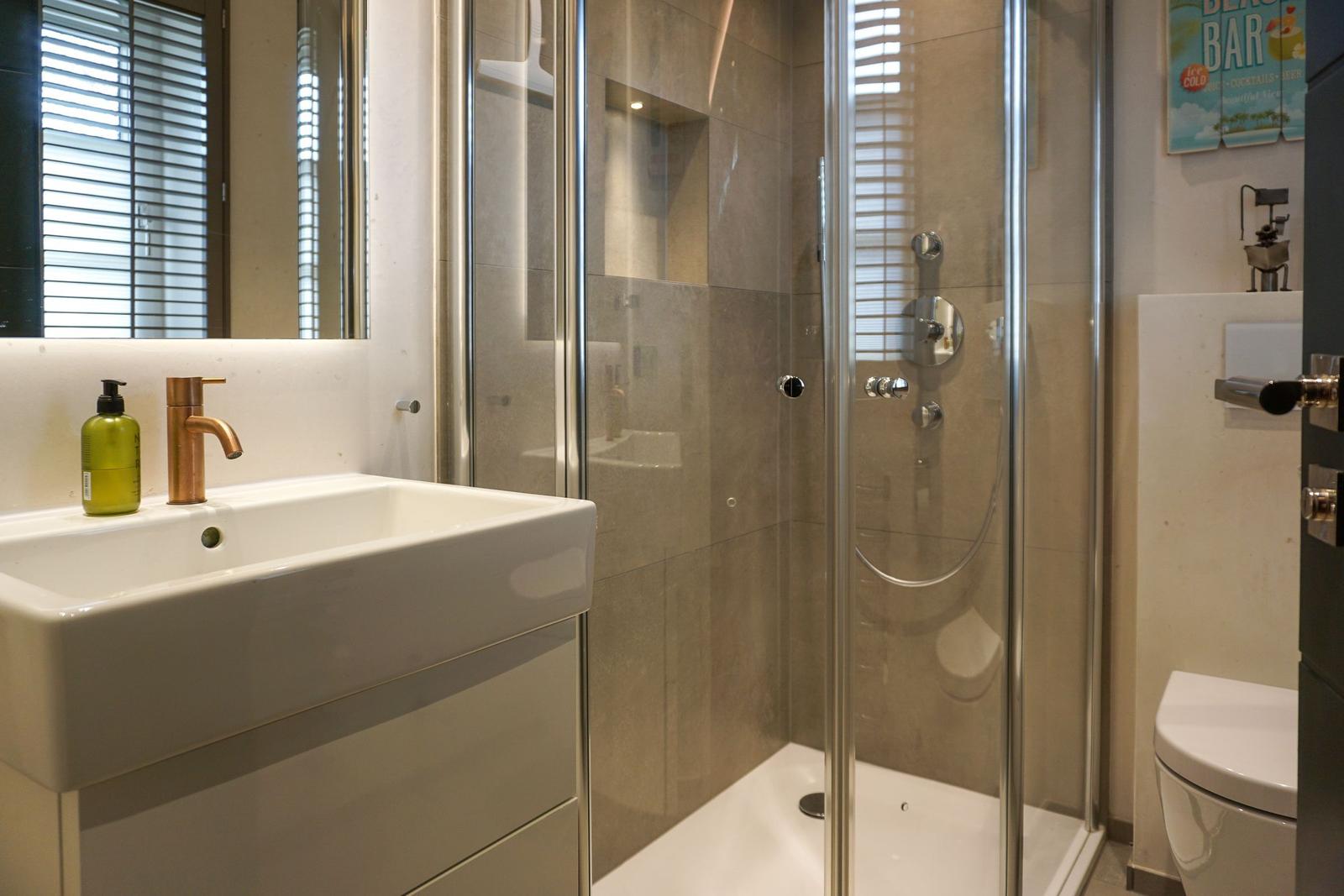 Bathroom with shower, sink, and toilet. Modern setup with glass shower.