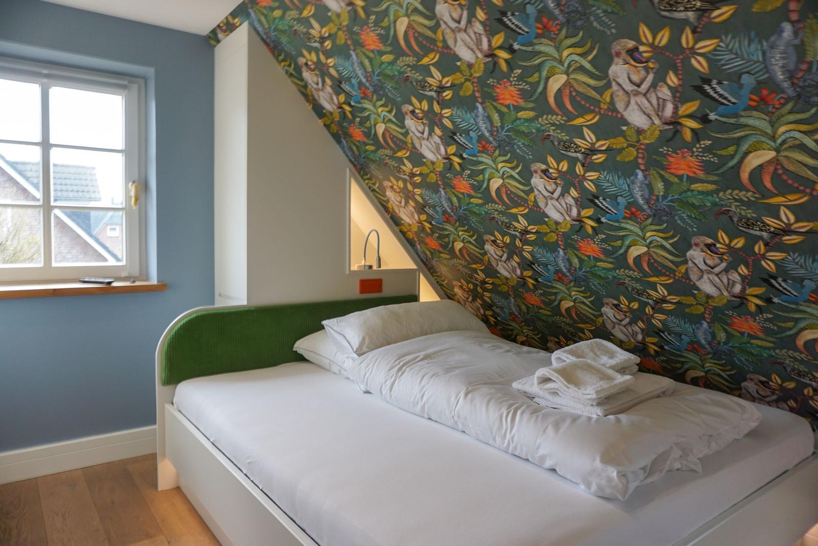 Bedroom with bed, window, and patterned wall.