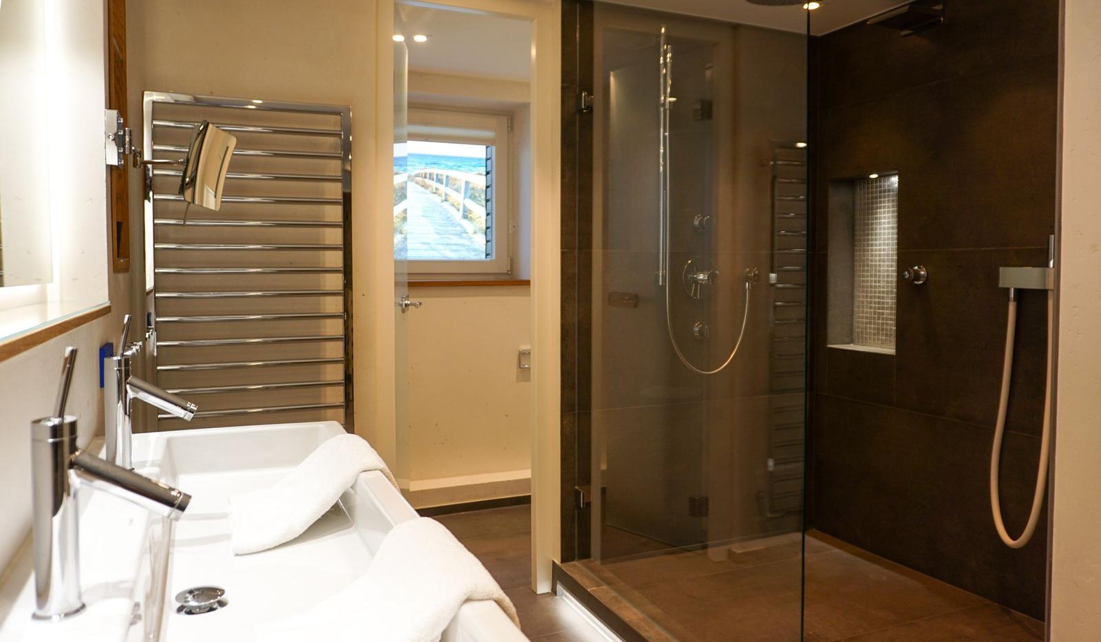 Bathroom with shower, sink, and sea view through window