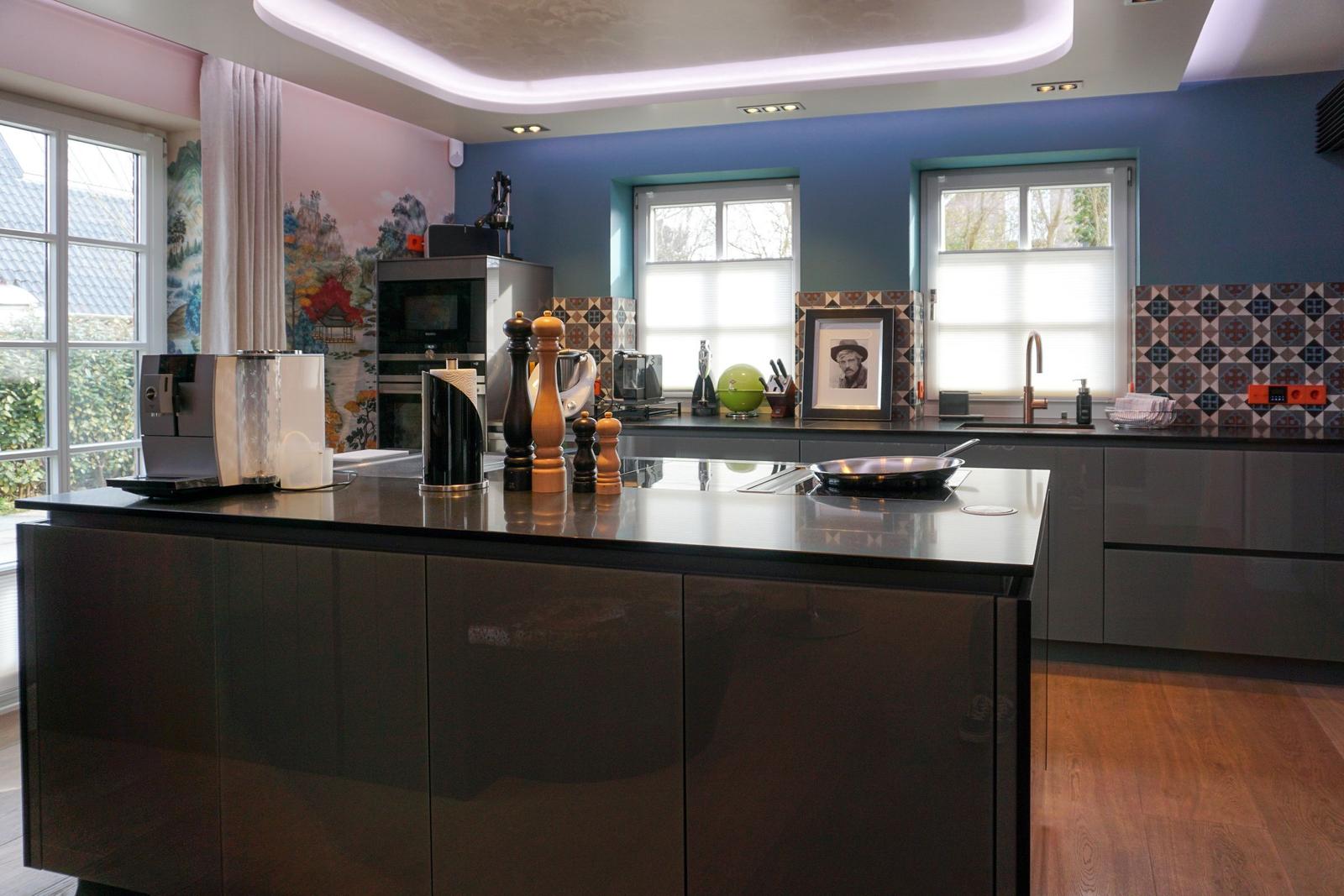 Modern kitchen with dark cabinets, kitchen island, and windows with view outside.