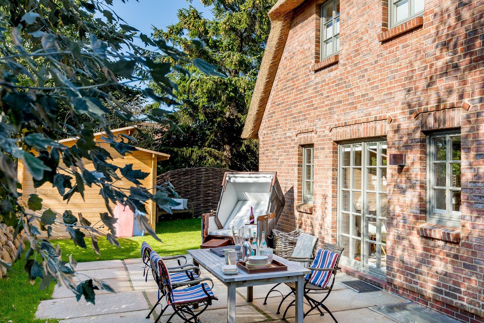 Backyard with table, chairs, and lounge area beside brick house.