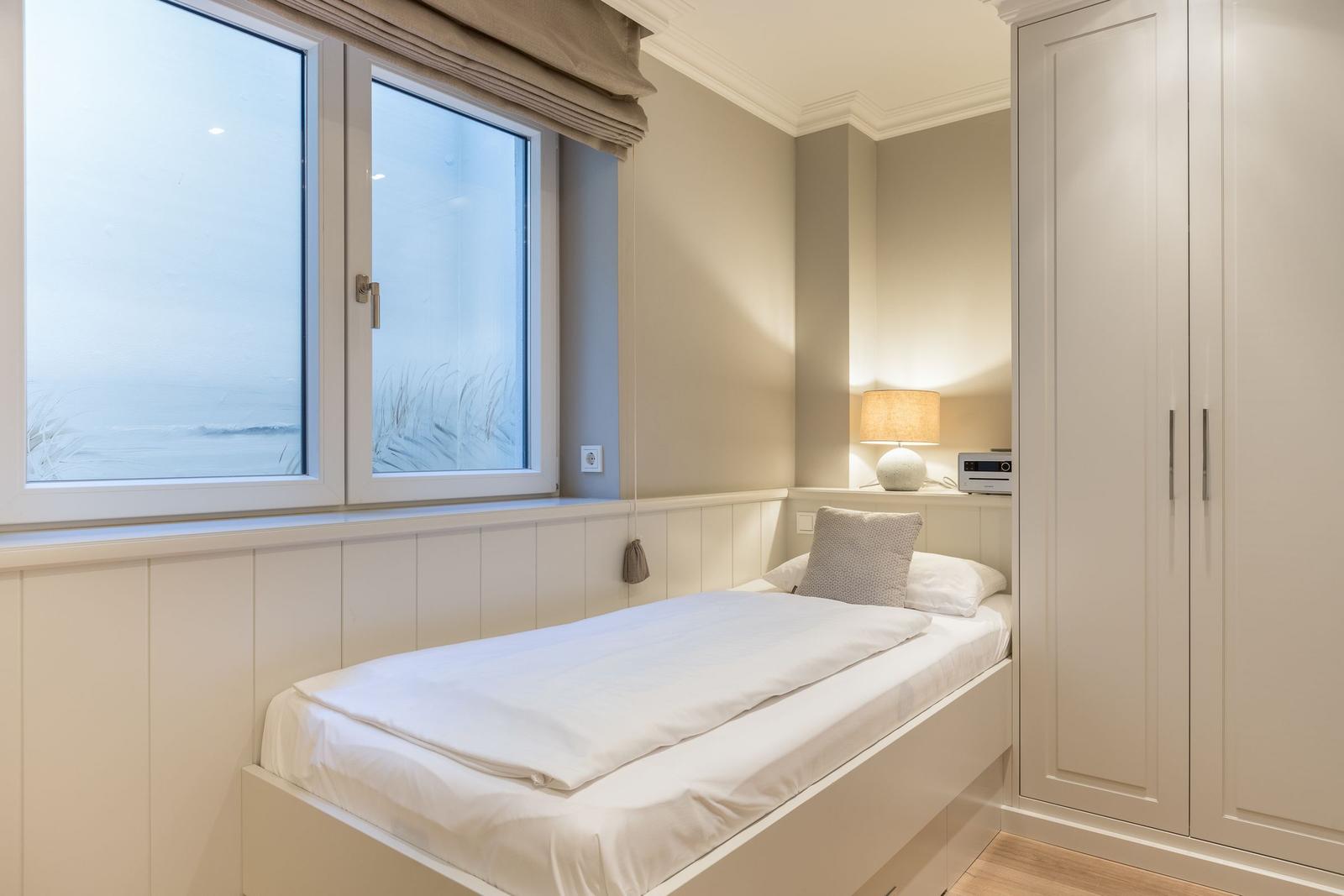 Bedroom with bed, wardrobe, and window with sea view.