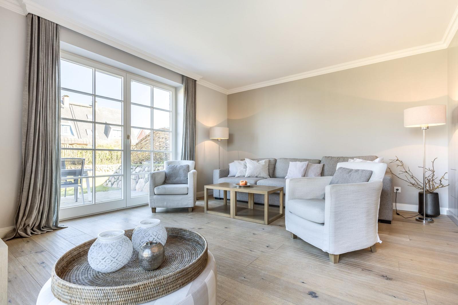 Living room with sofa, armchairs, and large window to terrace.