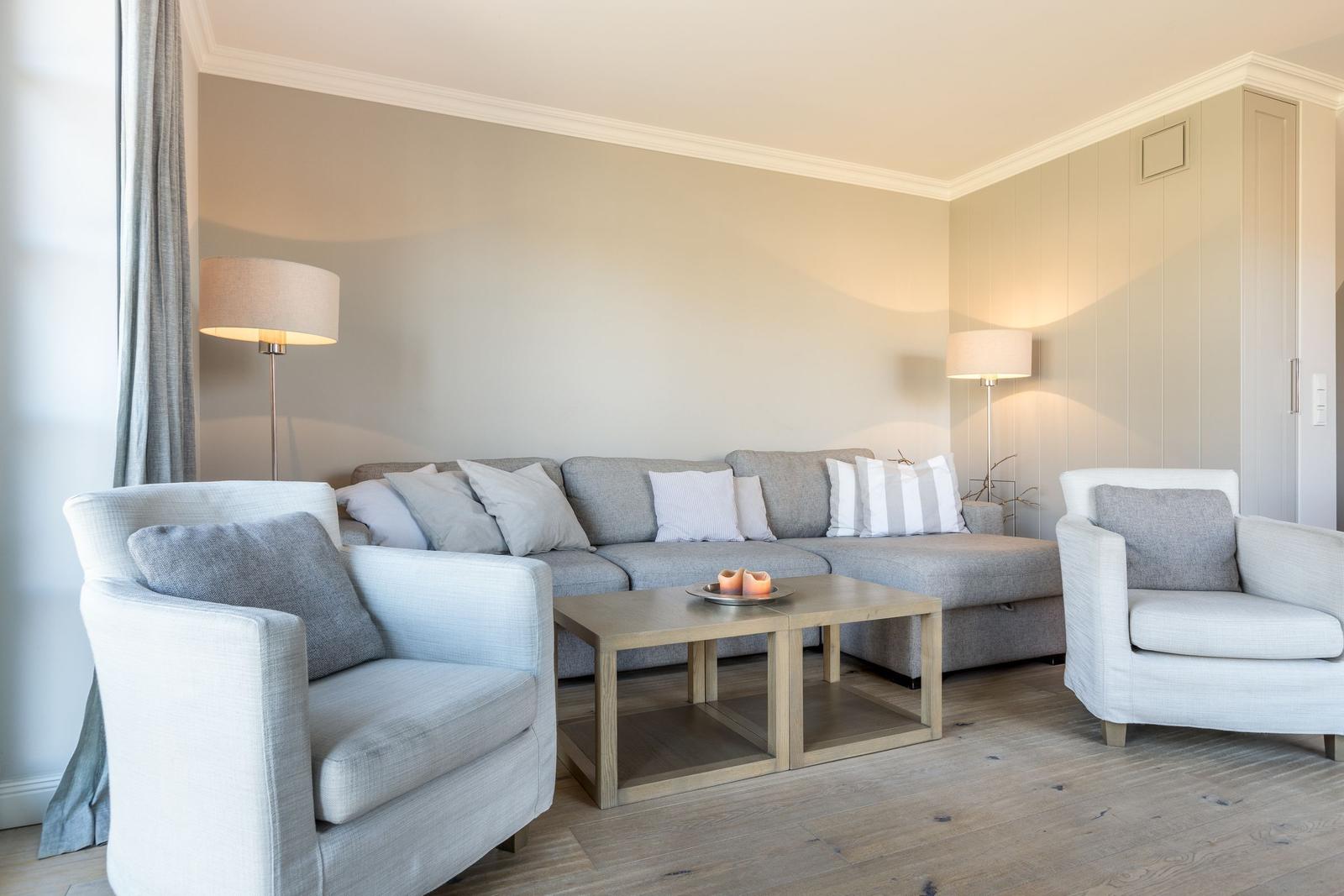 Living room with gray sofa, two armchairs, and wooden table.