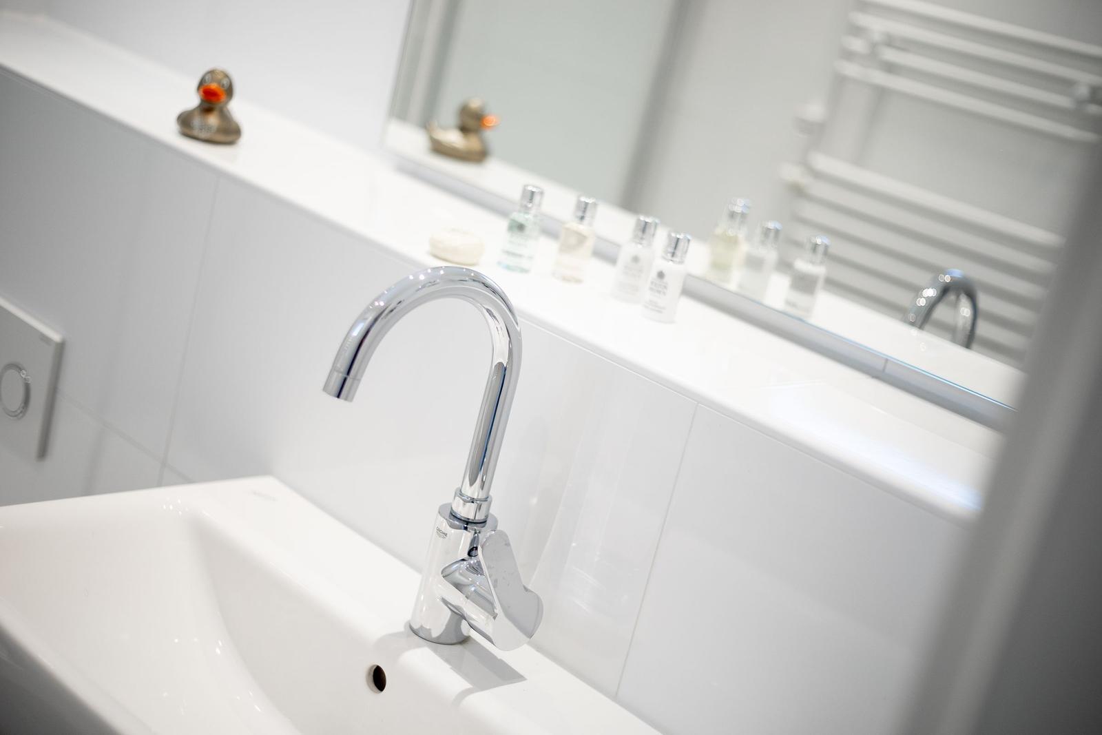 Bad mit Waschbecken, Spiegel und Duschbereich