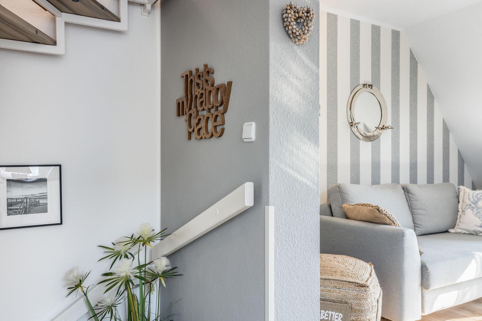 Living area with sofa and striped wall. Wall decor and plant are visible.