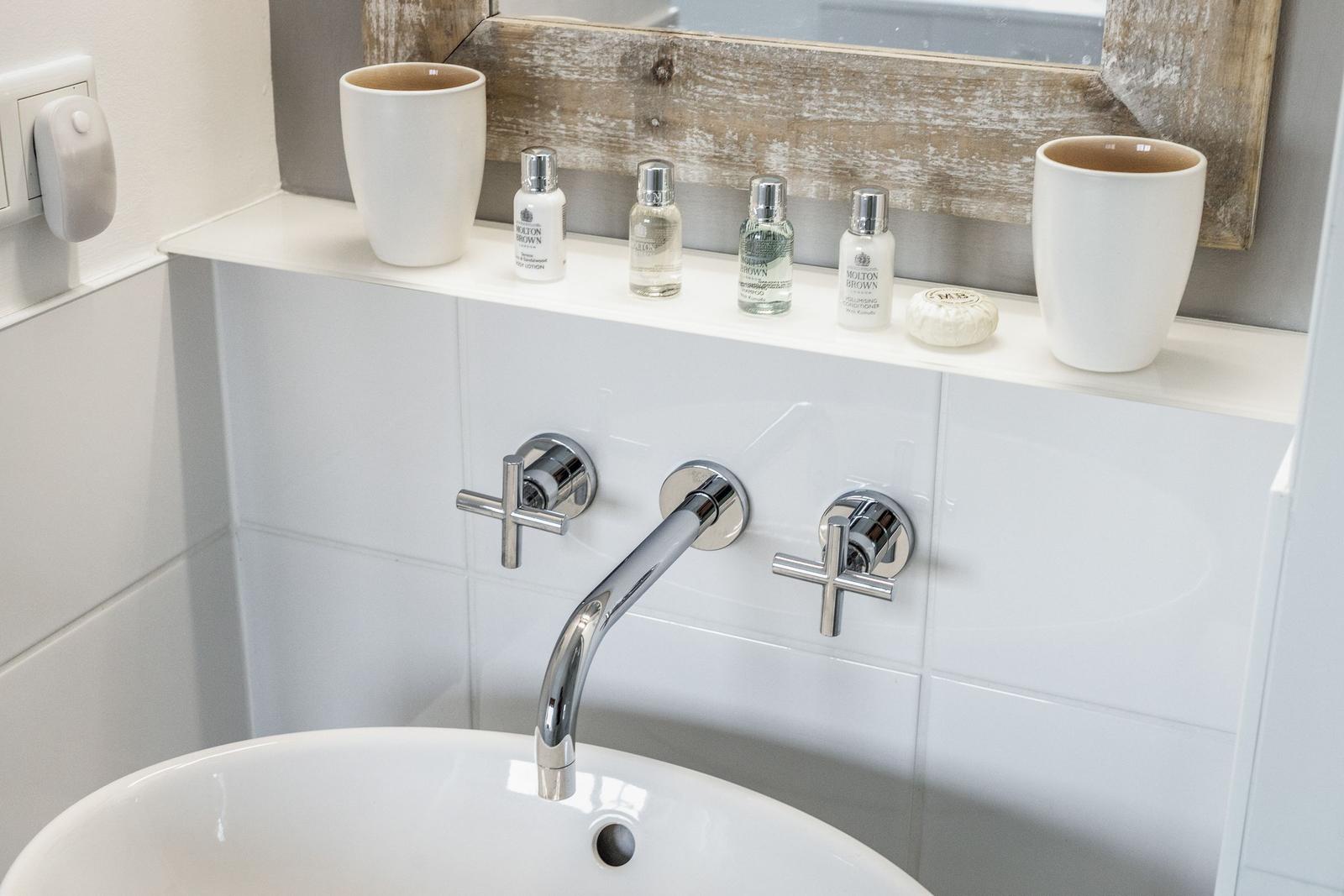 Sink with chrome faucet and care products on countertop