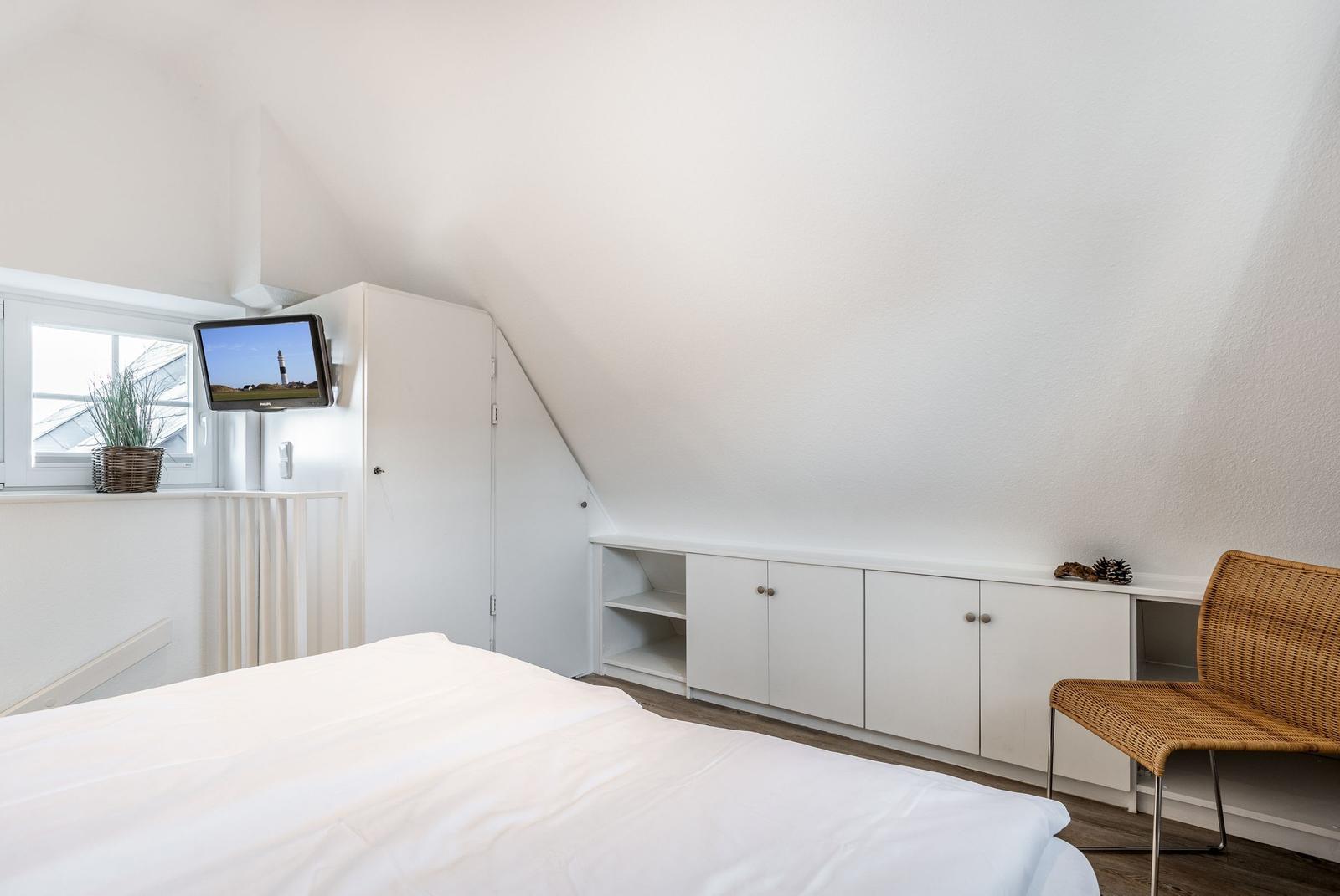 Bedroom with sloped ceiling, bed, cabinet, and chair