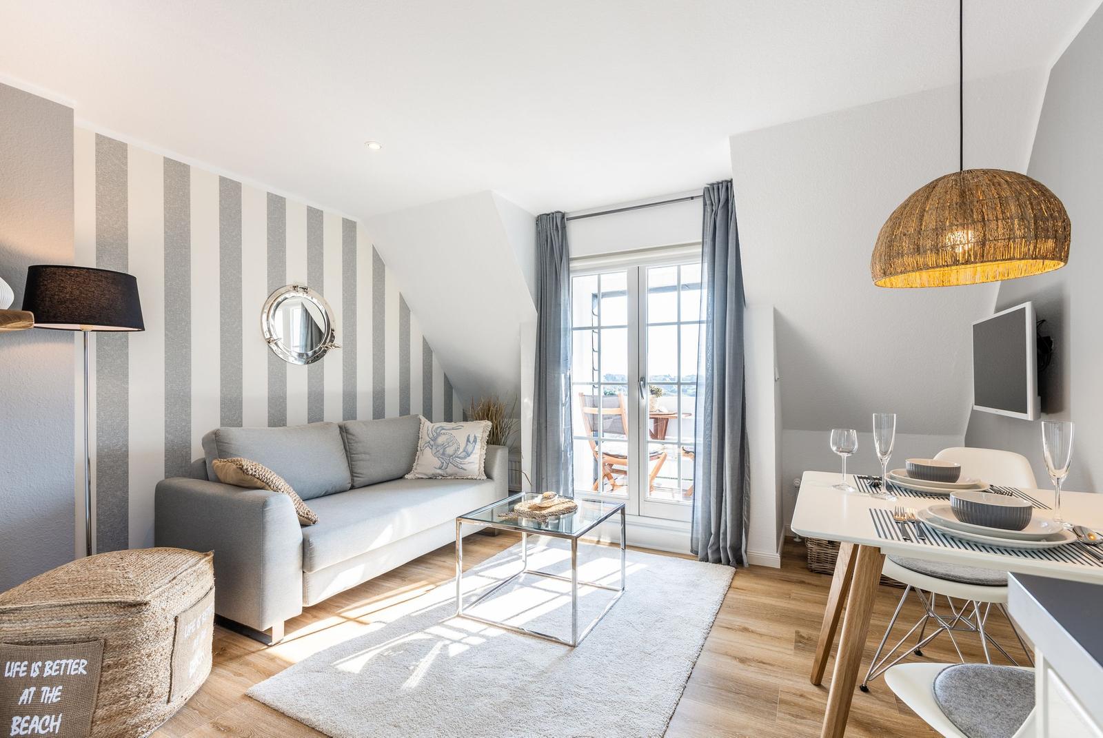 Living and dining area with sofa, table, and balcony access.