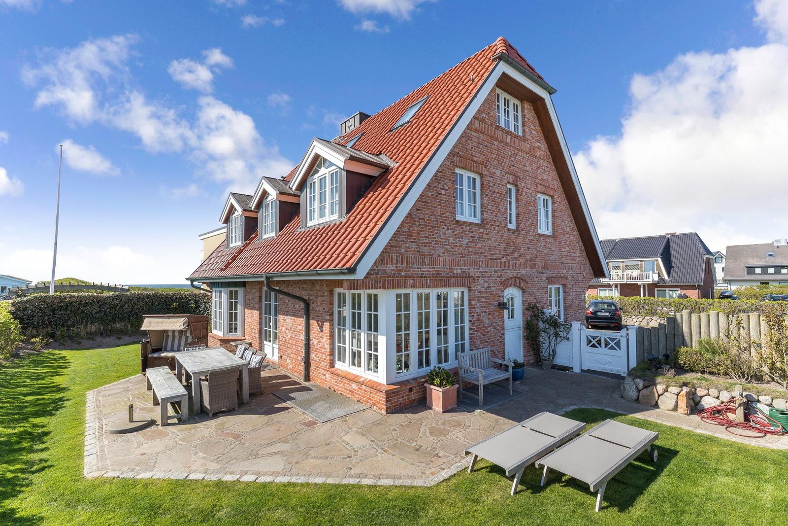 Red brick house with terrace and garden area. Garden furniture and sun loungers are available.