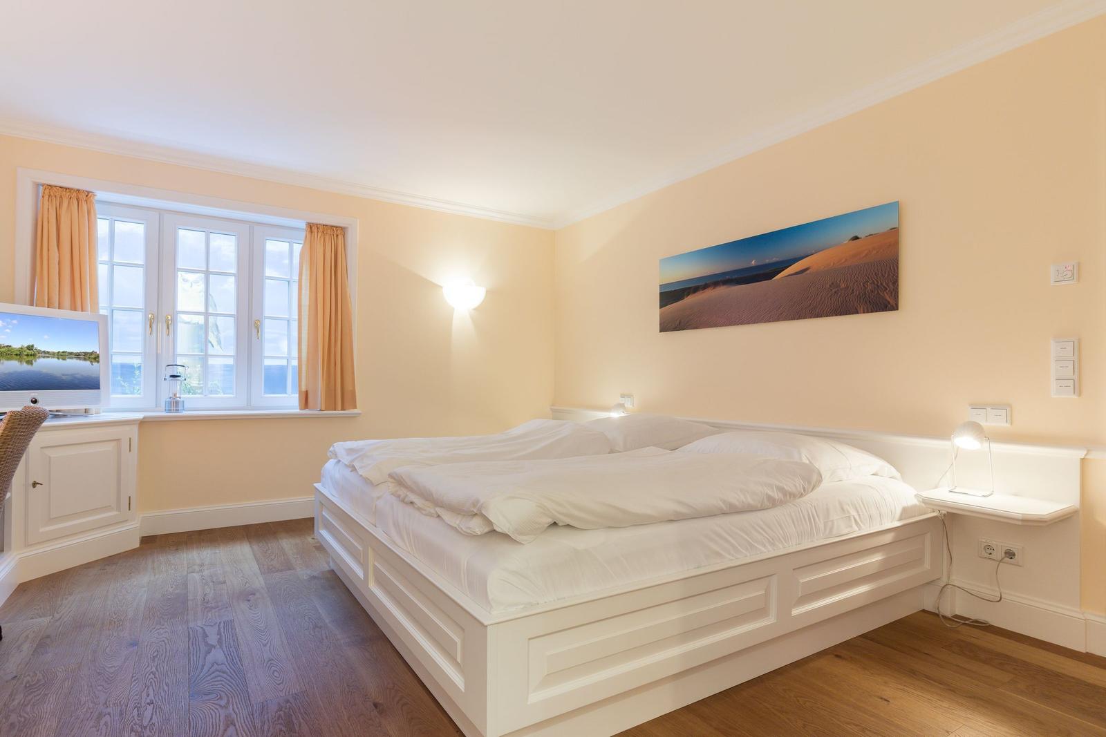 Bedroom with white bed, window, and wall art.