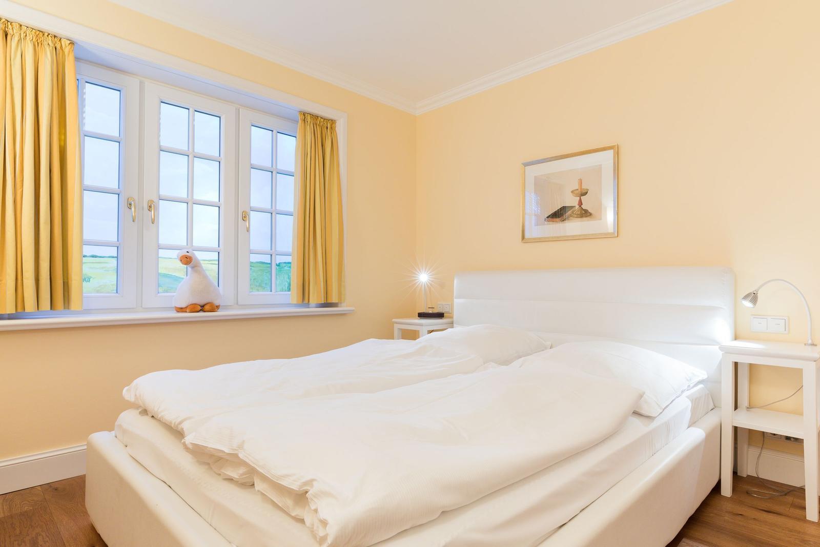 Bedroom with white bed, yellow walls, and window with yellow curtains.