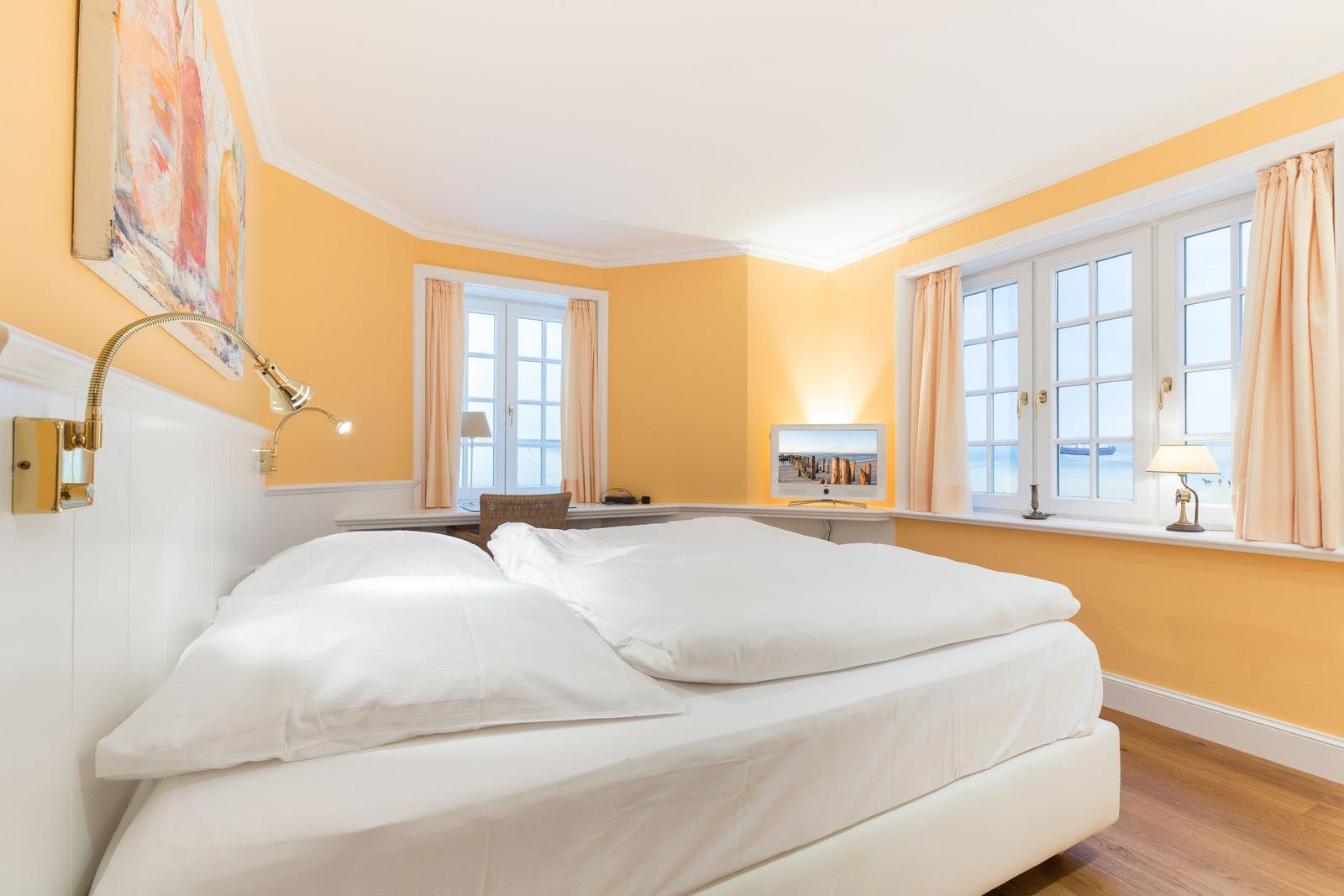 Bedroom with bed, windows, and wall art.
