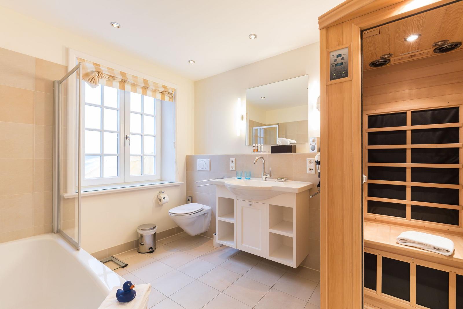 Bathroom with bathtub, toilet, sink, and sauna.