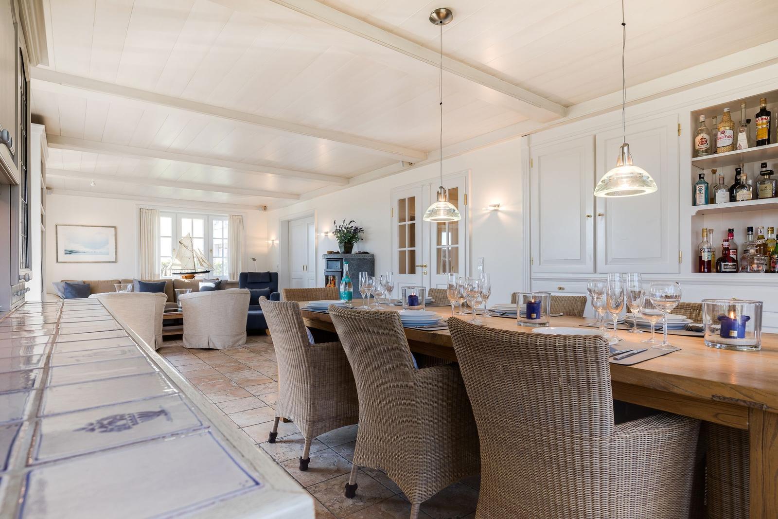 Dining area with table, chairs, and bar. Living area with sofa and fireplace in background.