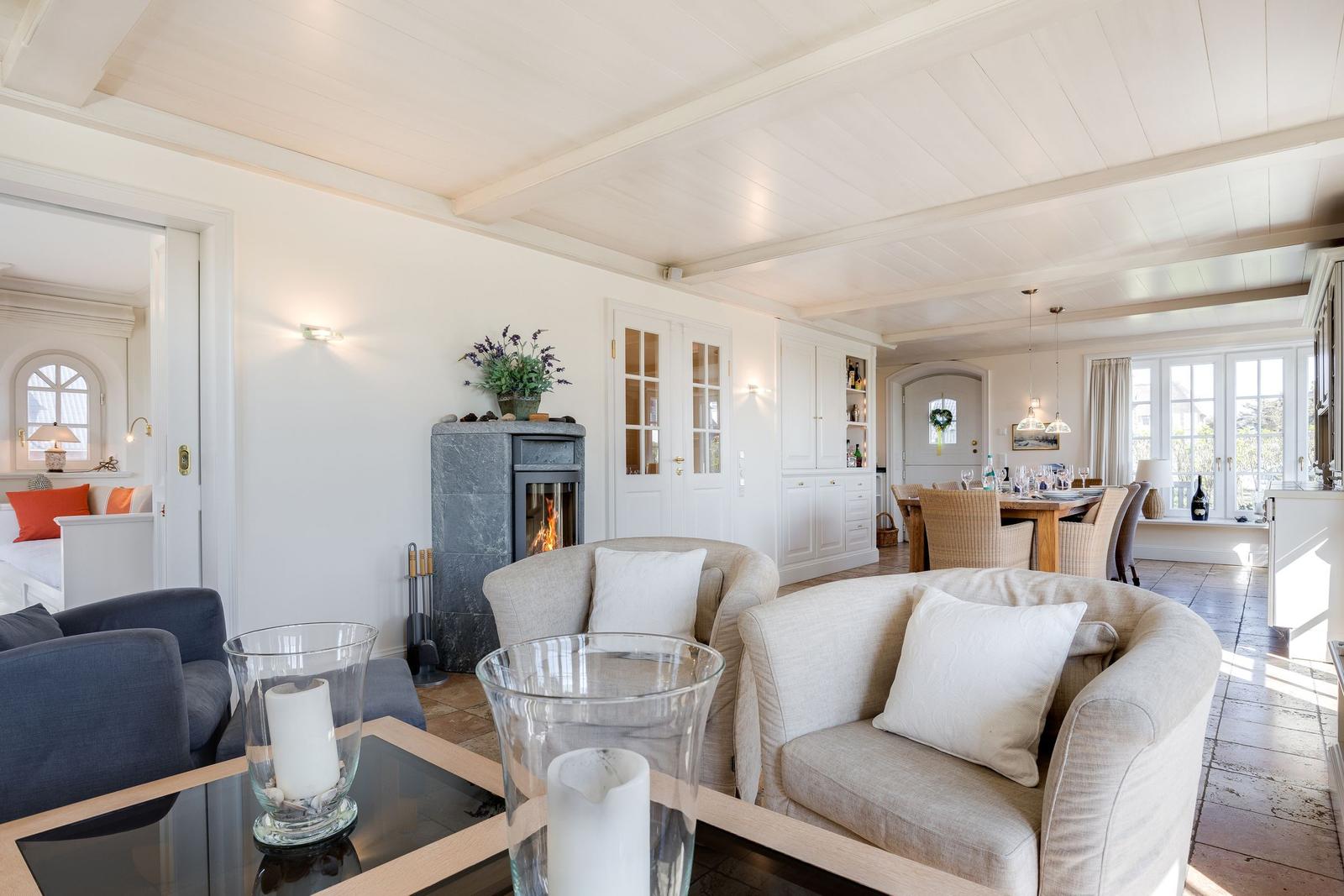 Living and dining area with fireplace, sofas, and table. Passage to bedroom.