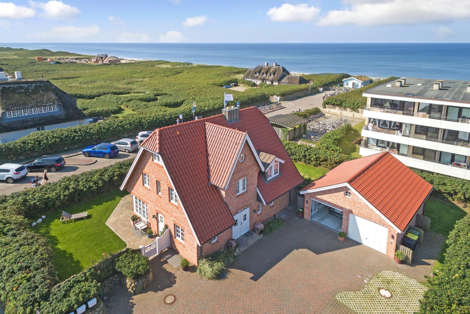 Red-roofed house with garage and garden. View of sea and dunes.