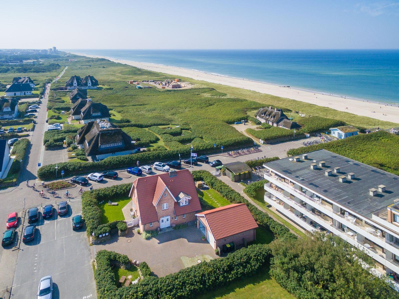 Haus mit rotem Dach, Strand und Grünflächen im Hintergrund